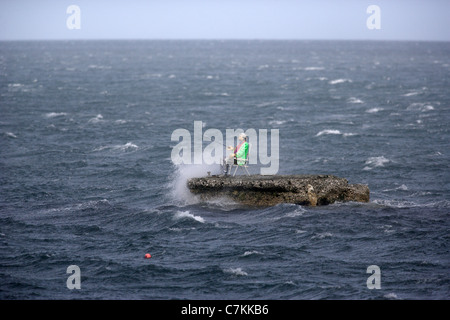 Un manichino vestito come un pescatore sorge su un promontorio roccioso nel mare d' Irlanda nei pressi del villaggio di Waterfoot, sulla contea di Antrim Foto Stock