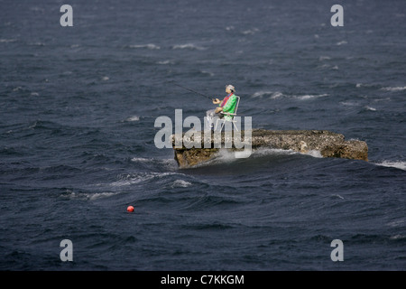 Un manichino vestito come un pescatore sorge su un promontorio roccioso nel mare d' Irlanda nei pressi del villaggio di Waterfoot, sulla contea di Antrim Foto Stock