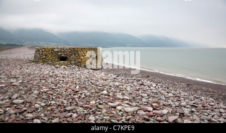 II Guerra Mondiale porta pillole sulla spiaggia di Baia Porlock nel Somerset con le colline di Exmoor oltre Foto Stock