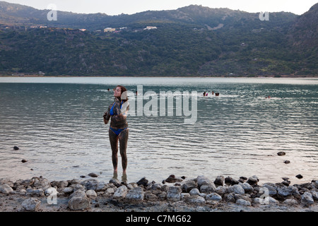 Donna coperto di fango in piedi nel lago, lago Specchio di Venere, isola di Pantelleria, Sicilia, Italia. Foto Stock