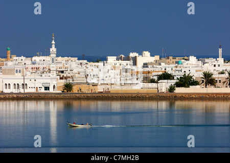 Barche a motore sulla laguna blu nella parte anteriore del case bianche della città portuale Sur presso il golfo di Oman, il sultanato di Oman Foto Stock