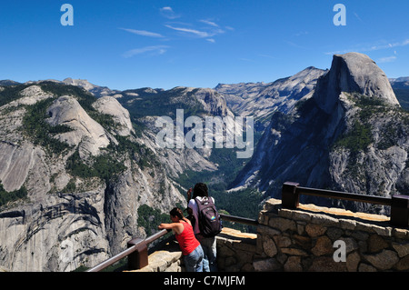 Una giovane coppia riposare godendo della vista dal punto ghiacciaio. Parco Nazionale di Yosemite in California, Stati Uniti d'America. Foto Stock