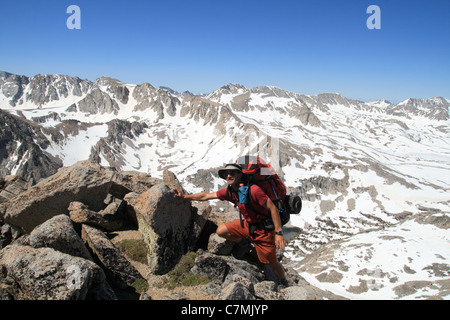 Un maschio backpacker con grandi pack si avvicina al vertice nella Sierra Nevada, in California Foto Stock
