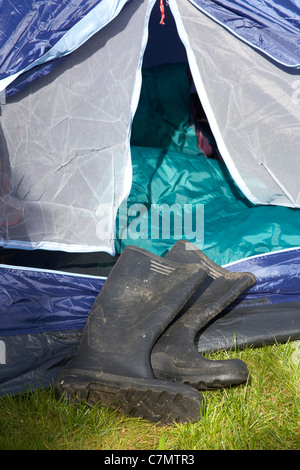 Sporchi stivali da pioggia disteso di fronte a un open tenda Foto Stock