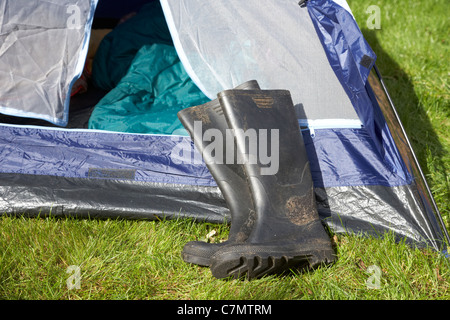 Sporchi stivali da pioggia disteso di fronte a un open tenda Foto Stock