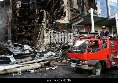 Thai fireman & camion dei pompieri, & la distruzione a sinistra dietro al Central World shopping mall, maglietta rossa protesta, Bangkok, Thailandia. Credito: Kraig Lieb Foto Stock