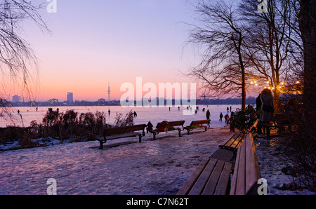 Saldamente Aussenalster congelato, Esterno lago Alster, dopo il tramonto, persone, divertimenti, ghiaccio, neve, in inverno, Amburgo, Germania Foto Stock