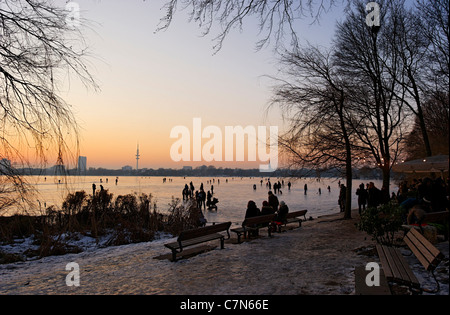 Saldamente Aussenalster congelato, Esterno lago Alster, dopo il tramonto, persone, divertimenti, ghiaccio, neve, in inverno, Amburgo, Germania Foto Stock