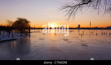 Saldamente Aussenalster congelato, Esterno lago Alster, dopo il tramonto, persone, divertimenti, ghiaccio, neve, in inverno, Amburgo, Germania Foto Stock