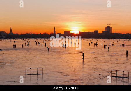 Saldamente Aussenalster congelato, Esterno lago Alster, dopo il tramonto, persone, divertimenti, ghiaccio, neve, in inverno, Amburgo, Germania Foto Stock