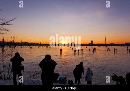 Saldamente Aussenalster congelato, Esterno lago Alster, dopo il tramonto, persone, divertimenti, ghiaccio, neve, in inverno, Amburgo, Germania Foto Stock