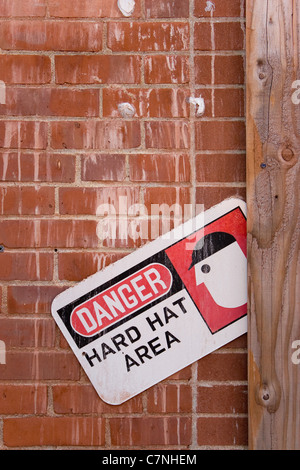 Un segnale di avvertimento che legge PERICOLO HARD HAT AREA. Foto Stock