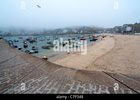 Vista dal porto attraverso il mare alla città a St Ives in Cornovaglia. Spiaggia e harbout barche anteriore sul mare seagull nel cielo Foto Stock