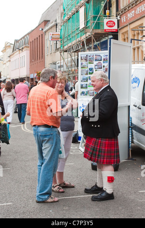 Membro del Glenmoriston Pipe Band in Suffolk parlando ai membri del pubblico a Bury St Edmunds sul giorno di mercato Foto Stock