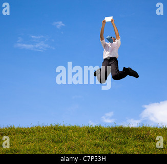 Happy businessman tenendo premuto il touch pad e i salti sulla collina Foto Stock