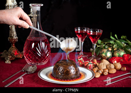 La mano che serve la masterizzazione di brandy su un Natale o budino di prugne Foto Stock