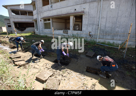 La polizia scavare il fango da scarichi in cerca di resti umani al di fuori Okawa scuola elementare di Ishinomaki, Giappone Foto Stock