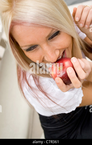 Una bionda business donna mordere in un fresco di Apple sulla sua pausa pranzo. Foto Stock