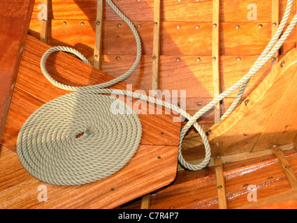 La corda avvolta sul ponte in teak. Avvolgimento decorativo è chiamato "cheesing' o 'bobina fiamminga' e stato usato per aiutare la corda a secco. Foto Stock