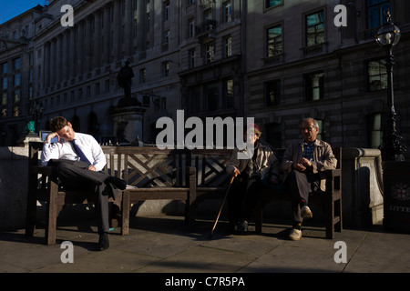 Un imprenditore dozes in autunno al sole con coppia di anziani nel triangolo della banca nella città di Londra. Foto Stock