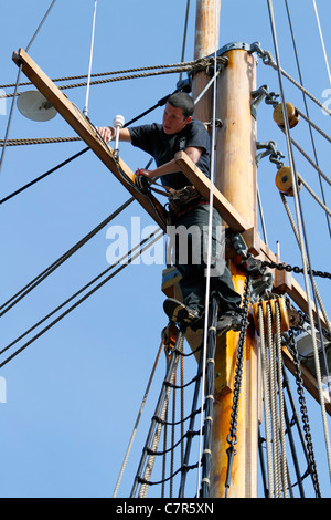 Giovane marinaio è la carteggiatura montante e oggetti in legno dell'altezza dell'attrezzatura di 35m topsail schooner Lilla Dan nel porto di Copenhagen Foto Stock