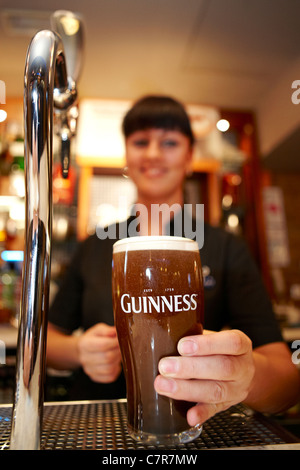 Bar cameriera serve una pinta di Guinness Foto Stock