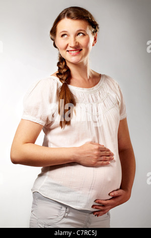Ritratto di bella donna incinta in bianco tanktop in isolamento Foto Stock