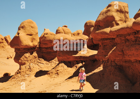 Una bambina cammina vicino weirdly modellate rocce in Goblin Valley State Park, Utah Foto Stock