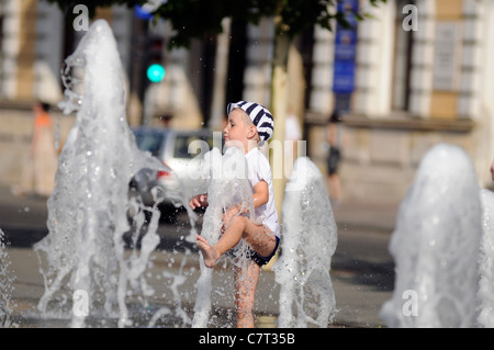 Kid giocando con acqua in una fontana. Sqare Unirii, Cluj Napoca (Romania). Foto Stock