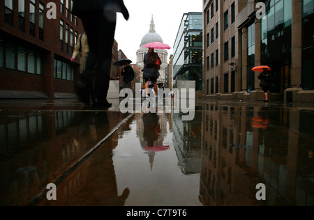 I pedoni a camminare lungo una piovosa Pietro collina verso la Cattedrale di St Paul, città di Londra, Regno Unito Foto Stock