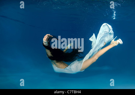 Una giovane donna con grandi capelli in posa di un subacqueo in piscina Foto Stock