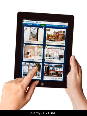 Mani tenendo iPad alla ricerca di una casa in vendita su Rightmove app su un tablet Foto Stock