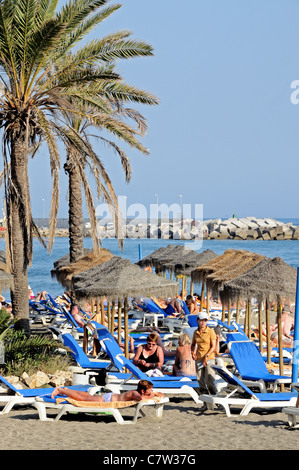 I turisti sulla spiaggia a Marbella, Costa del Sol, provincia di Malaga, Andalusia, Spagna, Europa occidentale. Foto Stock