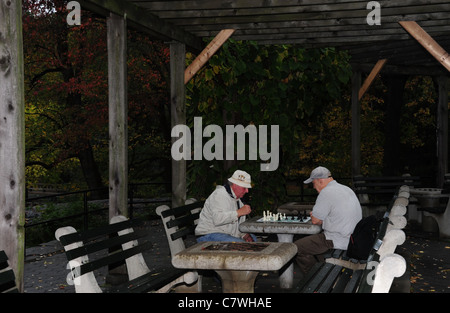 Due uomini anziani giocare a scacchi su un concreto piano di tavolo sotto la pergola, scacchi e dama House, al Central Park di New York City Foto Stock