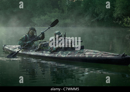 Navy SEALs navigare le acque in un folding kayak durante la guerra nella giungla delle operazioni. Foto Stock