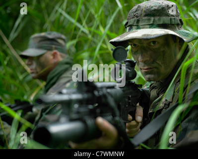 Stati Uniti Le forze speciali militari patrol attraverso l'erba alta durante il combattimento. Foto Stock