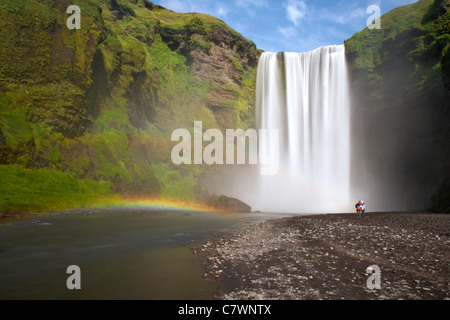 I turisti alla cascata Skogar nel sud-ovest dell'Islanda. Foto Stock