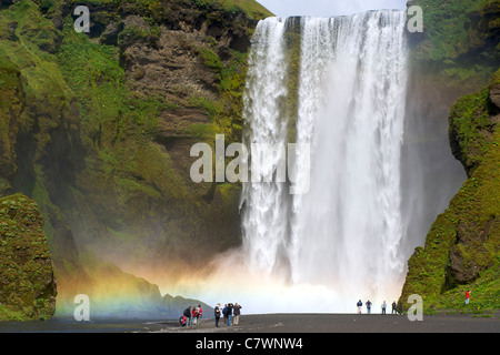 I turisti alla cascata Skogar nel sud-ovest dell'Islanda. Foto Stock