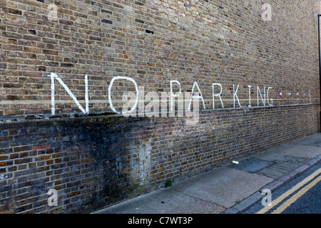 Nessun segno di parcheggio scritto su un muro di mattoni nei Docklands di Londra, Regno Unito. Foto Stock