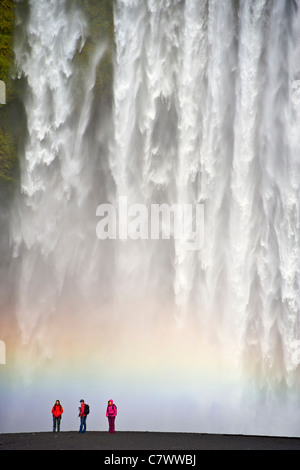 I turisti ai piedi delle cascate Skogar nel sud-ovest dell'Islanda. Foto Stock