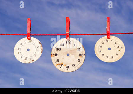 Tre orologi quadranti sulla stringa di colore rosso e il cielo Foto Stock