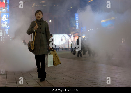 La metropolitana il vapore arriva attraverso gli sfiati in Via Wangfujing di Pechino in una fredda notte d'inverno Foto Stock