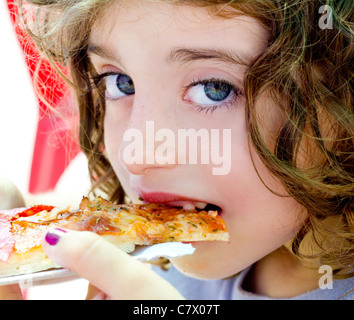 Gli occhi blu bambino ragazza mangiare la pizza slice fame Foto Stock