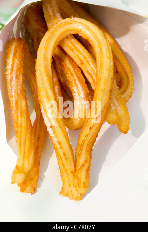 Churros fritti crullers spagnolo frittelle di farina nel cono di carta Foto Stock