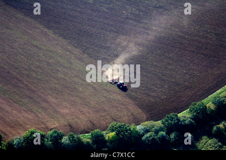 Vista aerea di un unico trattore in un campo a secco con polvere ondeggianti, coltivando il suolo asciutto, Foto Stock