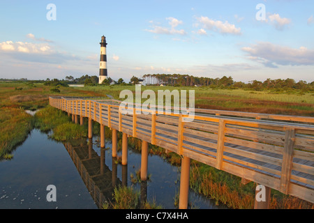 Passerella in legno per il Bodie Island Lighthouse sul Outer Banks del North Carolina contro un cielo blu e nuvole bianche Foto Stock