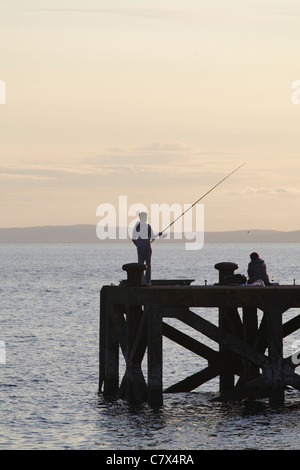 Pesca nel Firth of Clyde sul molo di Portencross al tramonto, nel Nord Ayrshire, Scozia, Regno Unito Foto Stock
