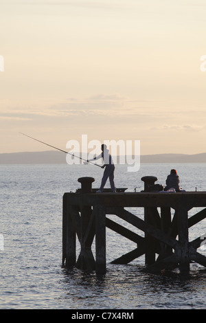 Pesca nel Firth of Clyde sul molo di Portencross al tramonto, nel Nord Ayrshire, Scozia, Regno Unito