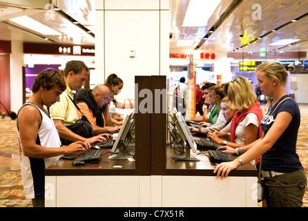 I passeggeri del trasporto aereo che utilizzano il computer nella sala partenze, l'Aeroporto Changi di Singapore asia Foto Stock