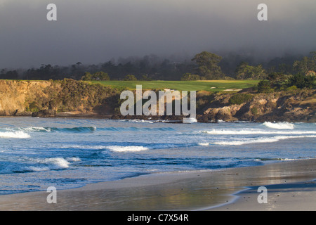 Onde che si infrangono sulla riva della spiaggia Carmel California, con il campo di golf di Pebble Beach in background Foto Stock